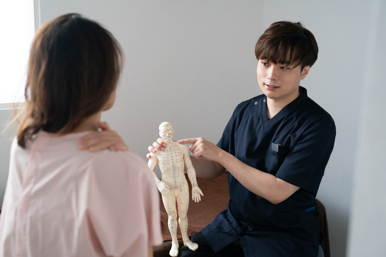 頭痛、肩こり、眼精疲労、不眠症、睡眠障害、倦怠感、慢性疲労症候群等でお悩みの患者様に問診とハリミンの説明をしている画像